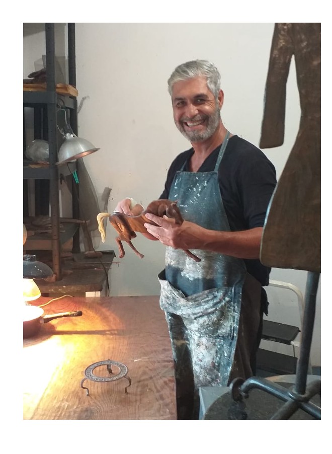 Luis Espiridión sonriendo mientras sostiene una escultura en su taller